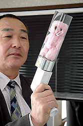 A developer of the party cracker that shoots out a teddy bear holds up the device at Sunamiya in Imabari, Ehime Prefecture, in April.